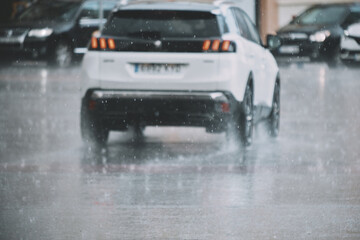 White suv driving through rainy street with blurred background, highlighting urban weather conditions