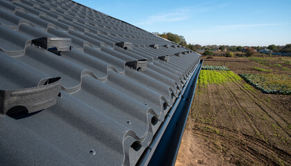 Metal roofing tiles with a wavy profile and a snow retainer on the edge