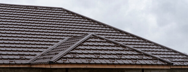 Brown wet roof made of metal tiles with diagonal joints © Sergey