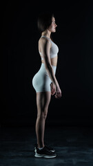 Naklejka premium Young beautiful woman with athletic body on dark background. Fitness girl 