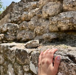 Hand touching ancient ruins - limestone pyramid in the jungle