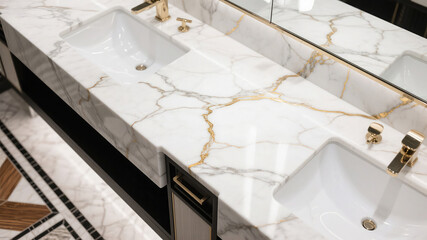 Luxurious modern bathroom interior featuring white marble countertop and golden faucets
