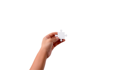 Hand holding a single white puzzle piece against a black background symbolizing solutions, teamwork, and problem-solving.