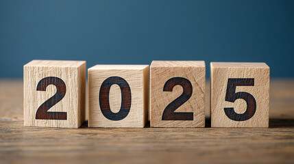 Wooden blocks displaying 2025 on a wood surface against a blue background, symbolizing the upcoming year and new beginnings