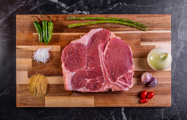 T-bone grueso crudo. Carne cruda de ternera porterhouse Filete sobre madera con hierbas y sal sobre fondo oscuro. Vista superior y espacio de copia.