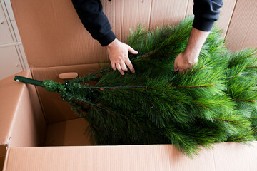 Adult caucasian male assembling artificial Christmas tree from cardboard box