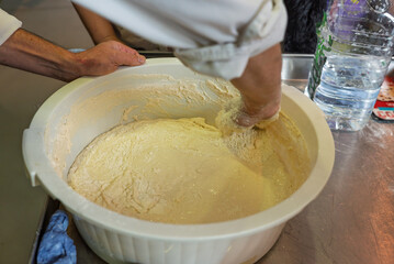 Hand of a man kneading water and flour for the preparation of bread dough.