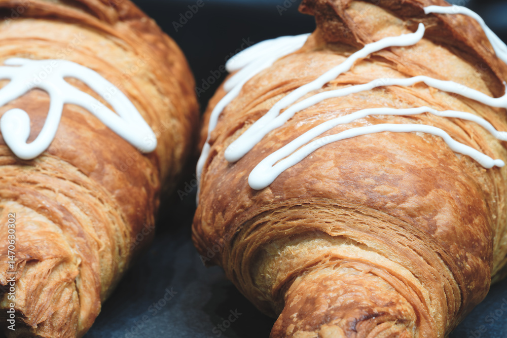 Leinwandbilder two croissants with white frosting on them. the frosting is in a zigzag pattern.