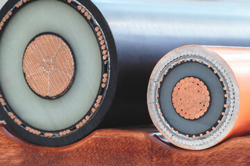 two high power copper wires in cross-section close-up, one of which is orange and other is black. orange wire is surrounded by a white layer, black wire is surrounded by a white and black layer.