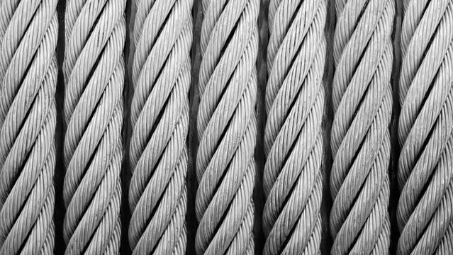 A close up of a wire rope with a black and white color scheme. rope is twisted and has a rough texture. Concept of strength and durability.