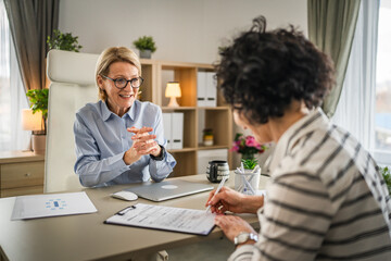 Two mature woman signature document, contract at work at office