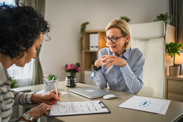 Two mature woman signature document, contract at work at office