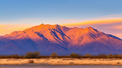 Naklejka premium Majestic mountain range bathed in sunset hues, with desert landscape in the foreground