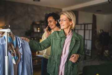 two mature women female friends at home choose sort clothes on hanger