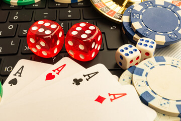 Colorful stock image showcasing casino items, such as dice, playing cards Ace of Spades, chips, and arranged on a keyboard Connotes themes of gambling, gaming, entertainment, risk-taking, financia