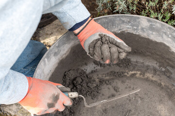 Obraz premium Construction worker wearing gloves mixes cement mortar in a bricklaying basin, ensuring the optimum texture for a strong bond