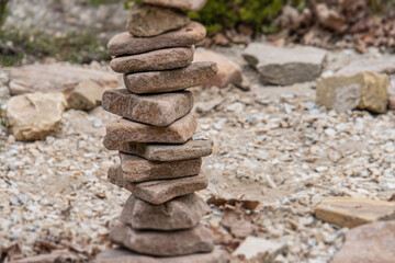 Top-down view of a precarious rock stack, varying in size and color, amidst scattered pebbles on natural terrain