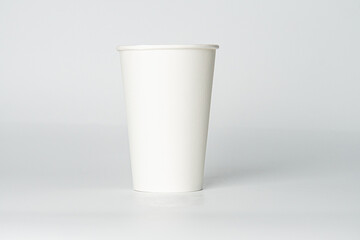 A white paper coffee cup with open lid on reflective surface, simple design, soft shadows, even lighting.