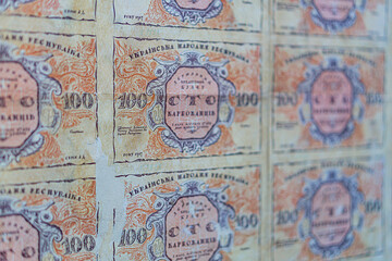 Historical, aged Ukrainian banknote pasted on a surface Features a portrait and intricate patterns in blues, greens, purples, and yellows Shows both left and right sides with 3D effect under natura