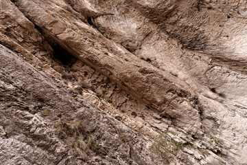 Natural rock formations showcase unique textures and patterns in a rugged canyon landscape during daylight.