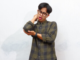 unhealthy  young Asian man in pain holding his elbow with a sad expression, isolated on a white...