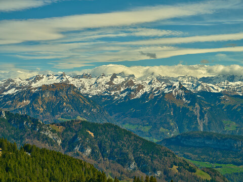 Mountain range showcasing snow-capped peaks and lush valleys under a clear blue sky in Switzerland during daytime - Powered by Adobe