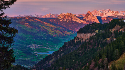 Majestic mountain landscape with vibrant sunset hues over the valley and peaks in Switzerland during early evening