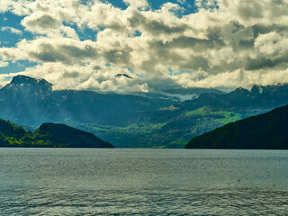 Majestic lake surrounded by mountains and dramatic clouds on a clear day in the Swiss landscape