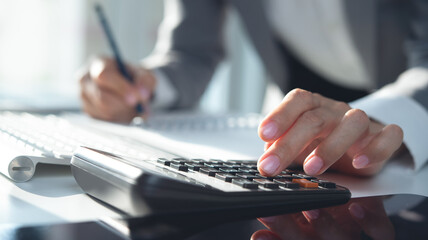 Close up, business woman working at office, using calculator to calculate company finance,...