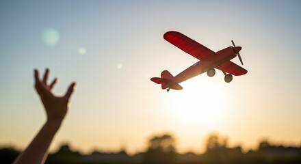 Child's Hand Reaching for a Toy Airplane at Sunset