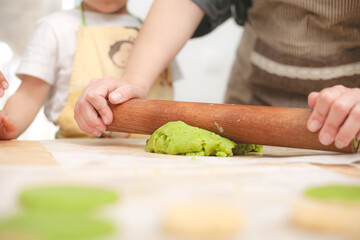 Obraz premium Close-up of mother flattening green cookie dough with wooden rolling pin