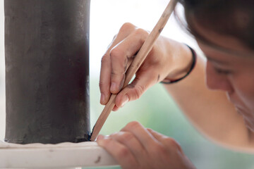 Ceramist outlining and detailing a ceramic piece.