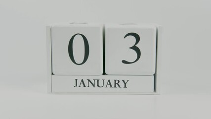A hand flips a wooden calendar from January 3rd to January 4th on a white background, marking the passing of time and the start of a new day