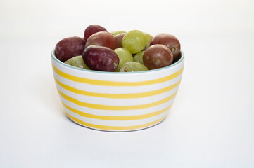 Close-up of fresh grapes in a small bowl, on a white background.
