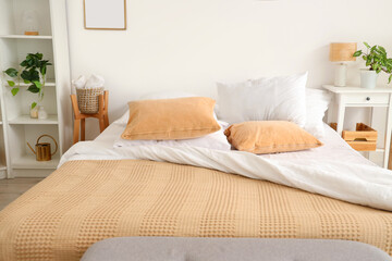 Obraz premium Cozy bed with soft pillows and beige blanket in light bedroom