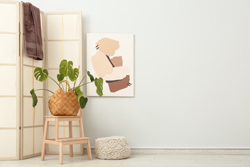 Interior of bathroom with folding screen, palm plant and painting