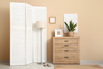 Interior of room with white folding screen, lamp and commode