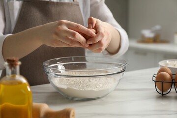 Making khinkali. Woman adding egg into bowl at table in kitchen, closeup
