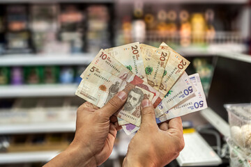 Shopping in a grocery store, close-up of hands with Colombian pesos