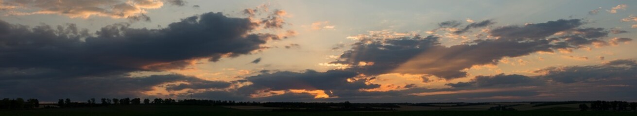 Landscape at sunset. Tragic gloomy sky. Panorama. Crimson twilight. Heavy, gloomy, dark clouds.