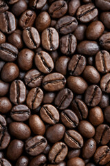 Naklejka premium A close-up macro view captures the rich texture and warm brown colors of scattered, roasted coffee beans filling the entire frame