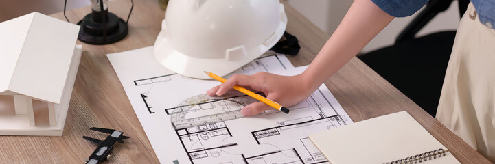 Architect Asian Women Design House Plans by Hand with Protractor and Pencil Using Blueprints for Construction Design on Wood Table