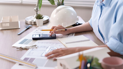 Asian adult Architect Designing Blueprint with Calculator Asian Architect at Work Reviewing Construction Plan for Building Design Using Calculator