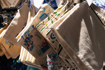 Greek Canvas Souvenir Bags. Souvenir canvas bags featuring Greek-themed designs hanging in a Zakynthos market.