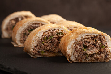 Savory fish rolls with herbs served on a dark slate board ideal for gatherings or casual meals