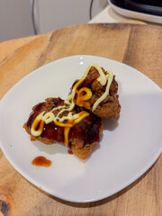 A stack of deep-fried boneless chicken pieces with spicy sauces and mayo. Crispy outside, juicy and succulent inside, smelling delicious.