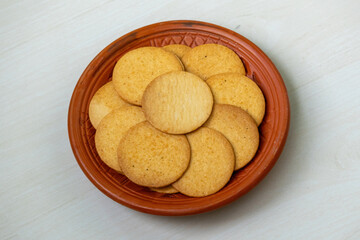 Crispy and spicy biscuits on a clay plate on a wooden table. These biscuits taste like a delightful combination of chips and biscuits. They can be enjoyed as an afternoon snack or during leisure time.