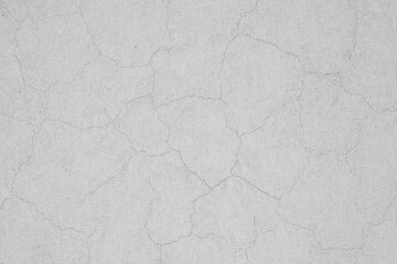 Cracks in the wall after plastering and painting. Old cracked concrete wall texture background. White painted plaster with thin cracks in a building wall.
