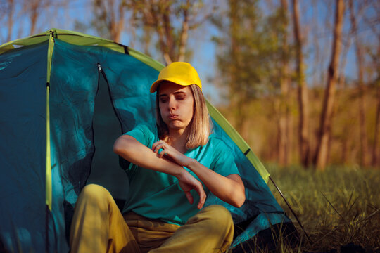 Woman Sitting in a Tent Being Bothered by Itchy insect Bites. Person scratching herself from mosquitoes bites because she camped outside. 
