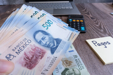 Acercamiento a billetes de 500 pesos mexicanos, cerca de mesa, en la mesa hay más dinero y una nota que dice 